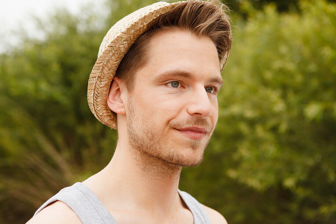 Young man wearing a strawhat, Munich, Bavaria, Germany