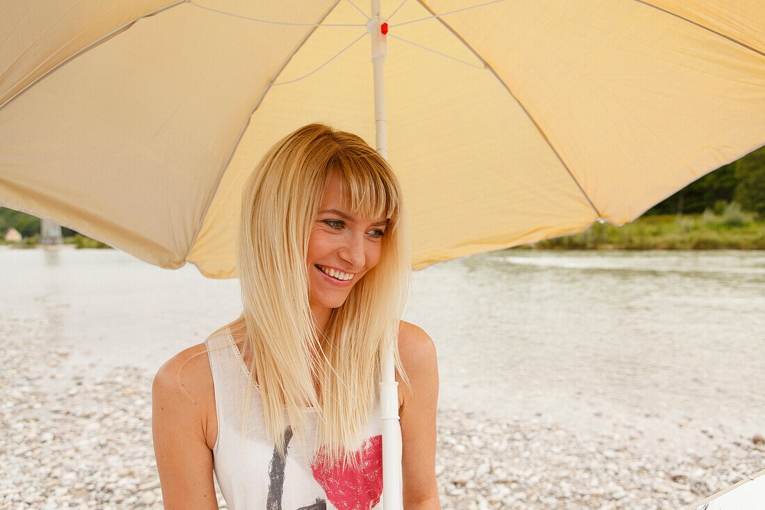 Young woman with a sunshade on Isar riverbank, Munich, Bavaria, Germany