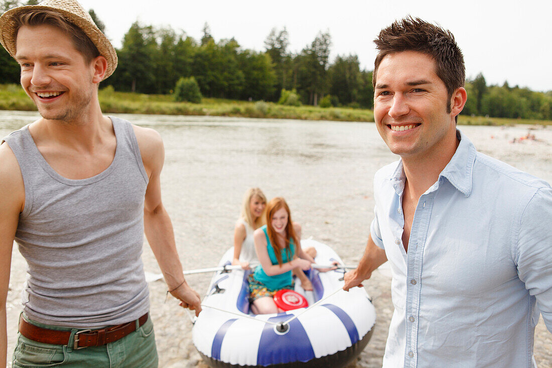 Young people with a rubber dinghy at the Isar river, Munich, Bavaria, Germany