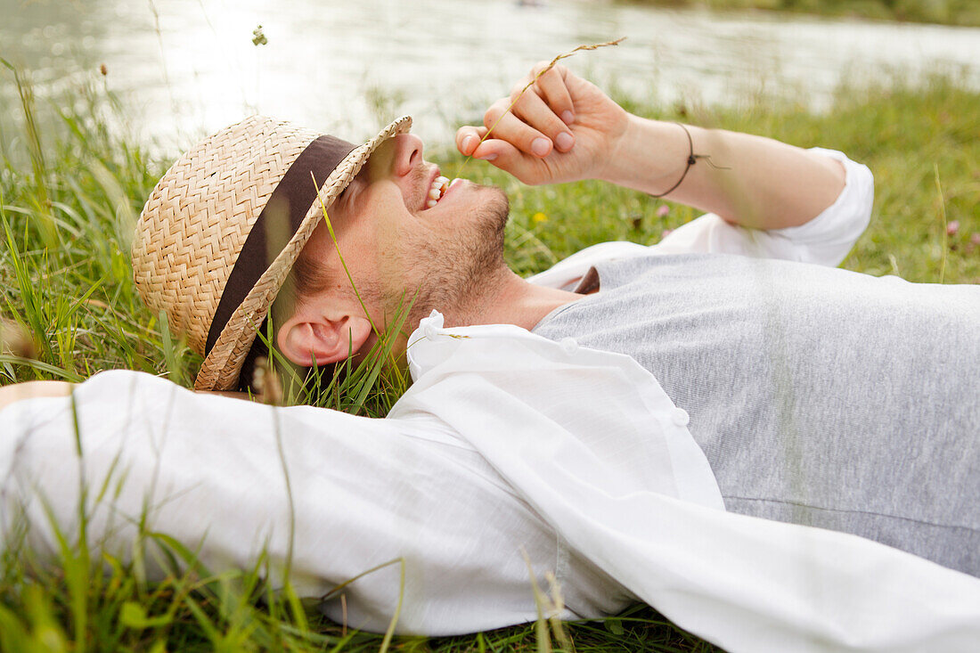 Young man lying on the Isar riverbank, Munich, Bavaria, Germany