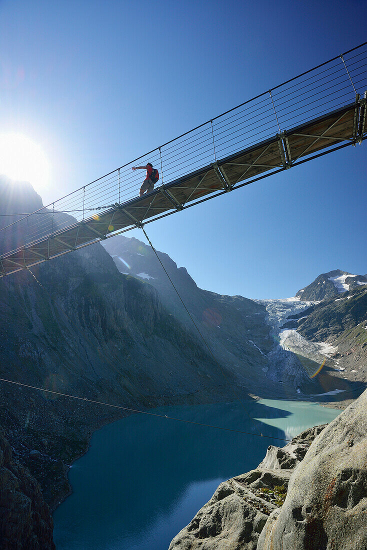 Wanderer geht auf Hängebrücke über Gebirgssee, Triftgletscher im Hintergrund, Triftbrücke, Tieralplistock, Urner Alpen, Berner Oberland, Bern, Schweiz