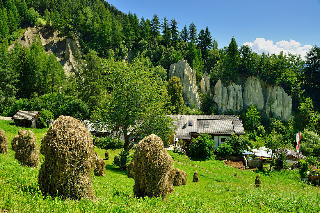 Hay stacks with restaurant and earth pyramids of Terenten in the background, Terenten, Puster valley, South Tyrol, Italy