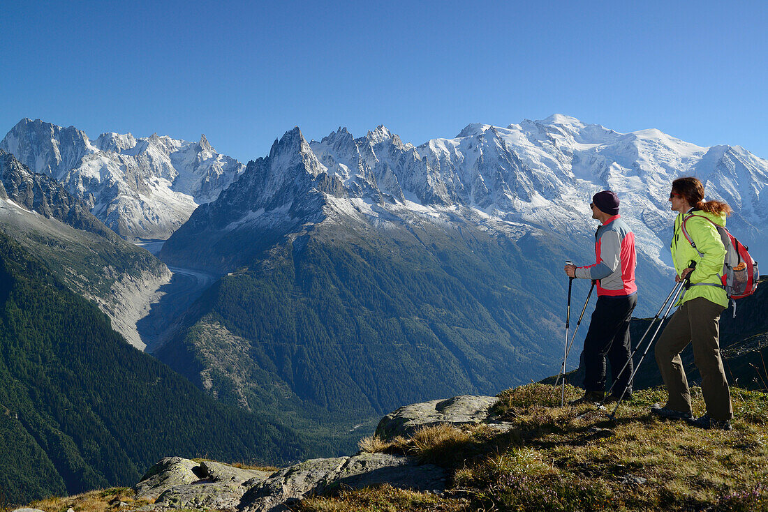 Frau und Mann beim Wandern genießen Aussicht auf Grandes Jorasses, Aiguilles du Chamonix und Mont Blanc, Mont Blanc-Gruppe, Mont Blanc, Chamonix, Savoyen, Frankreich