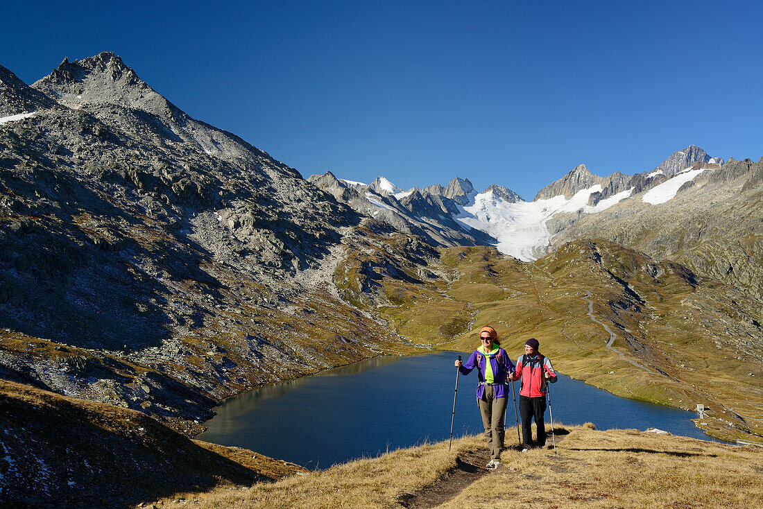 Frau und Mann wandern an Bergsee mit Blick Oberaarhorn und Finsteraarhorn, Berner Alpen, Berner Oberland, UNESCO Welterbe Schweizer Alpen Jungfrau-Aletsch, Schweiz