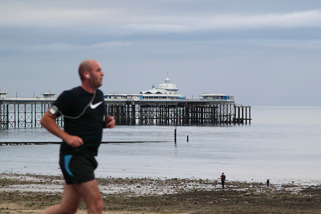 Jogger at the promenade in front of the pier of seaside resort Llandudno, North Wales, Great Britain, Europe
