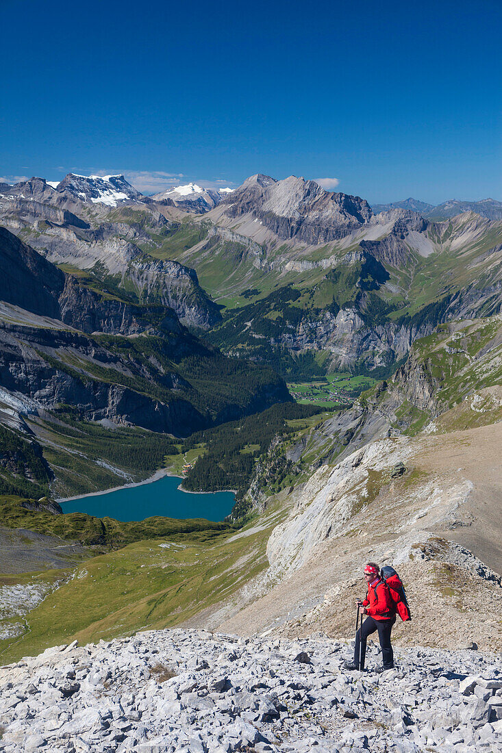A man hiking, view to Oeschinensee, Kandersteg, Kandertal from the ridge between Schwarzhorn and Bundstock, Bernese Oberland, Canton of Bern, Switzerland