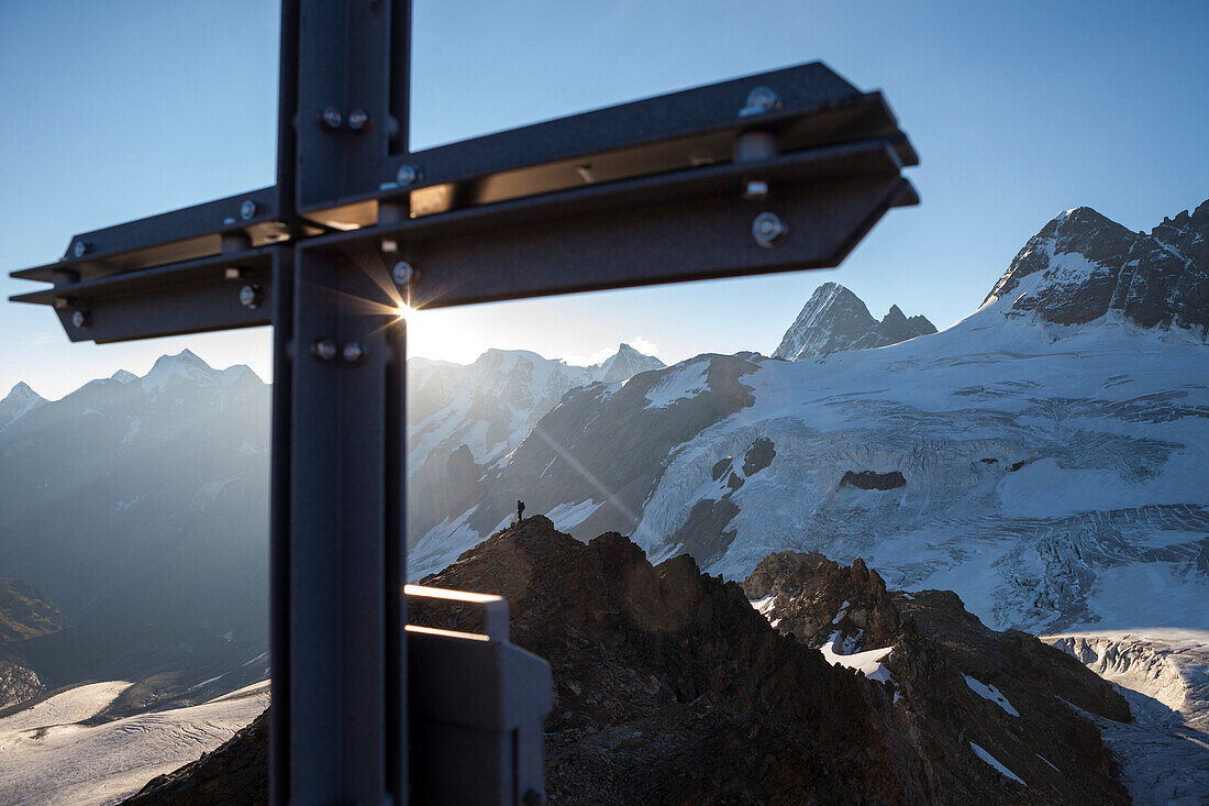 Summit cross and mountaineer on the ridge of Mount Mutthorn, Bernese Oberland, Canton of Bern, Switzerland