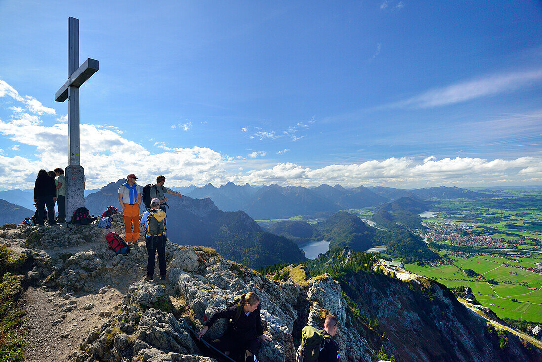 Hikers standing on the summit of Tegelberg, view to Fuessen, Tegelberg, Ammergau range, Allgaeu, Swabia, Bavaria, Germany