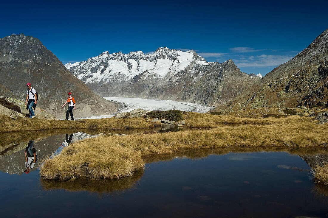 Wanderndes Paar am Bettmersee, Bettmeralp, im Hintergrund das Berner Oberland, Kanton Wallis, Schweiz, Europa