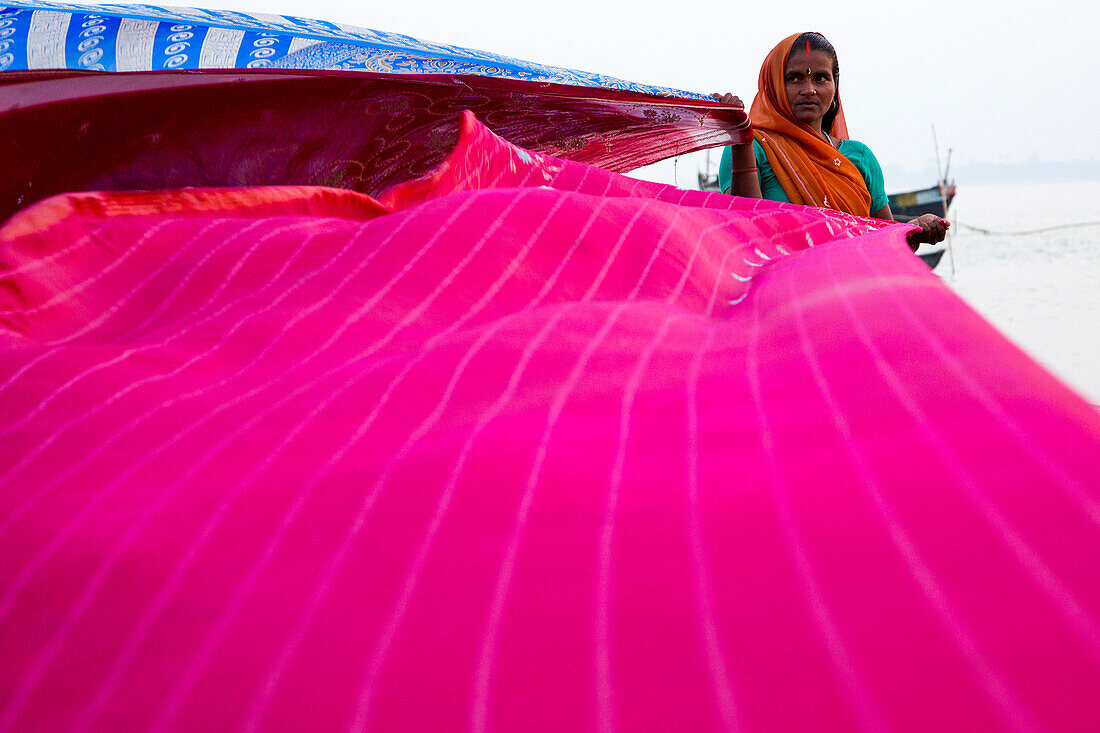 Woman dries sari cloths on banks of Ganges river, Simaria, Bihar, India