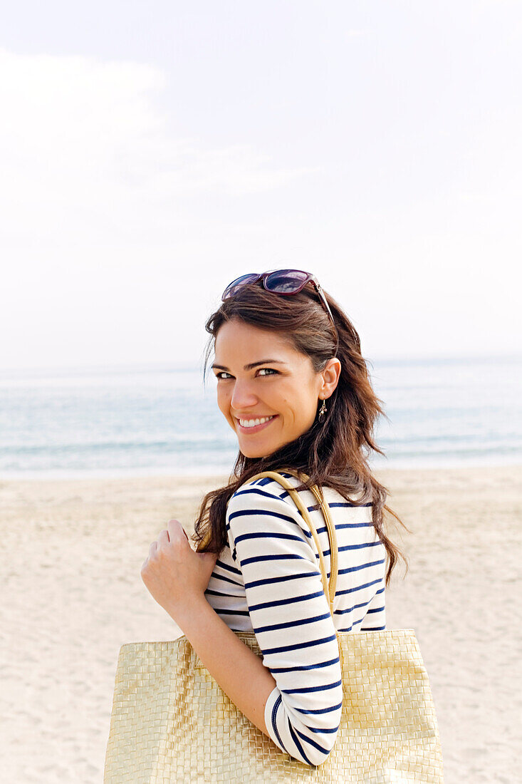 Portrait of a young brunette woman arriving at the beach