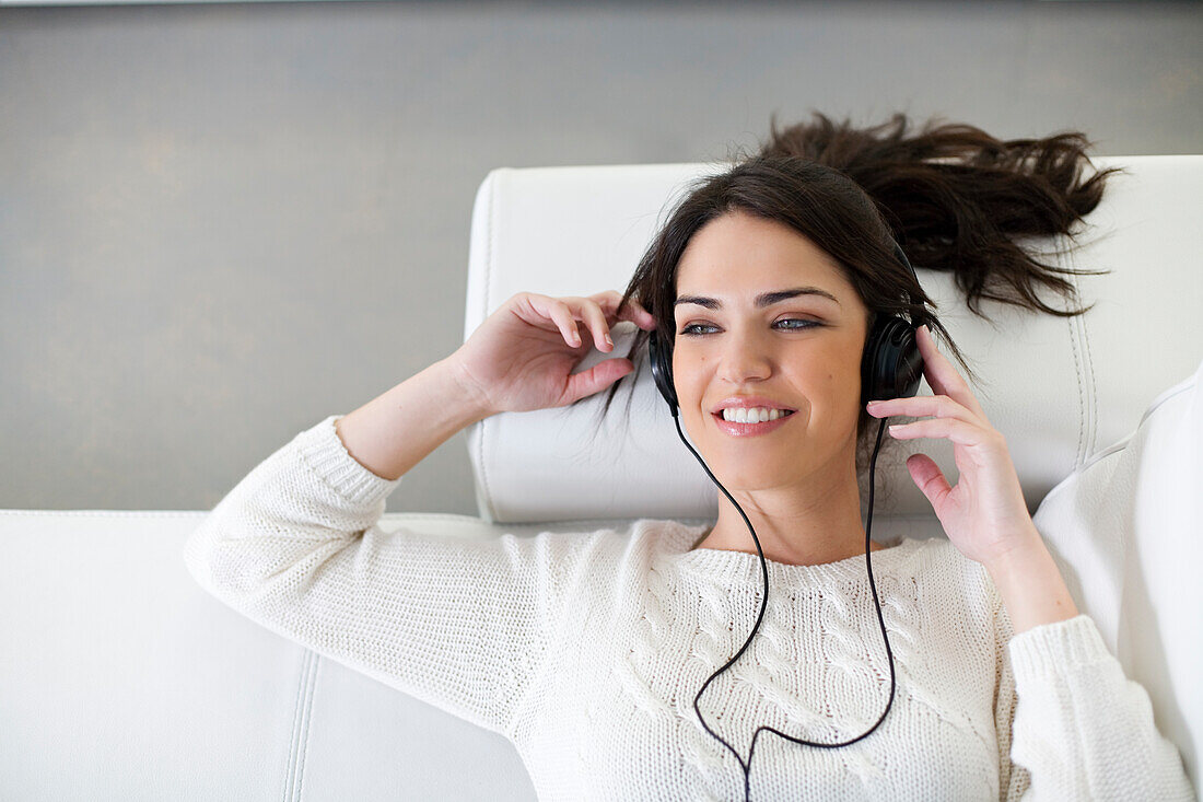 Pretty woman with headphones on the sofa