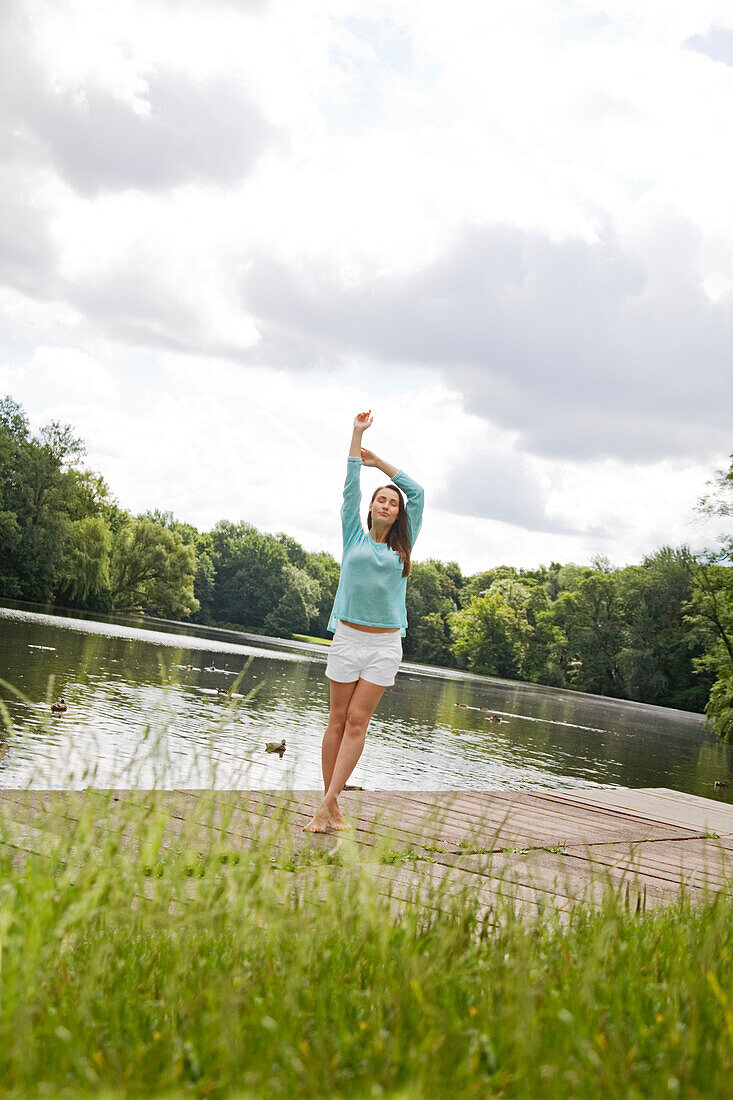 Pretty woman stretching by a lake