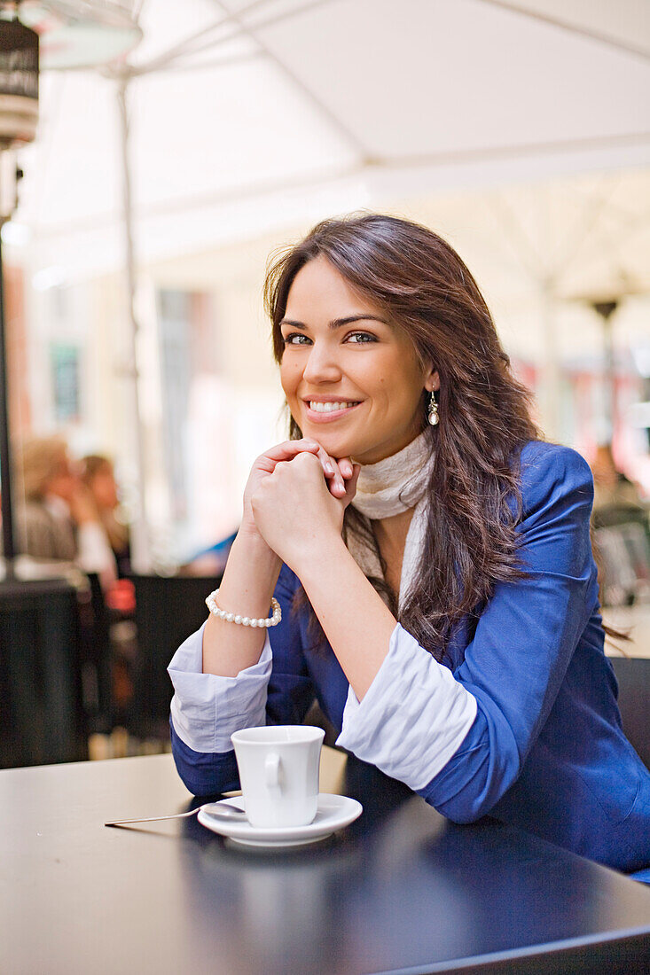 Pretty woman enjoying a coffee in a Cafe, smiling at camera