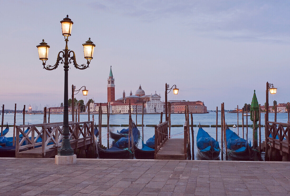 Traditional gondolas moored along the waterfront in Venice, looking towards the island of Church of San Giorgio Maggiore. Dawn.