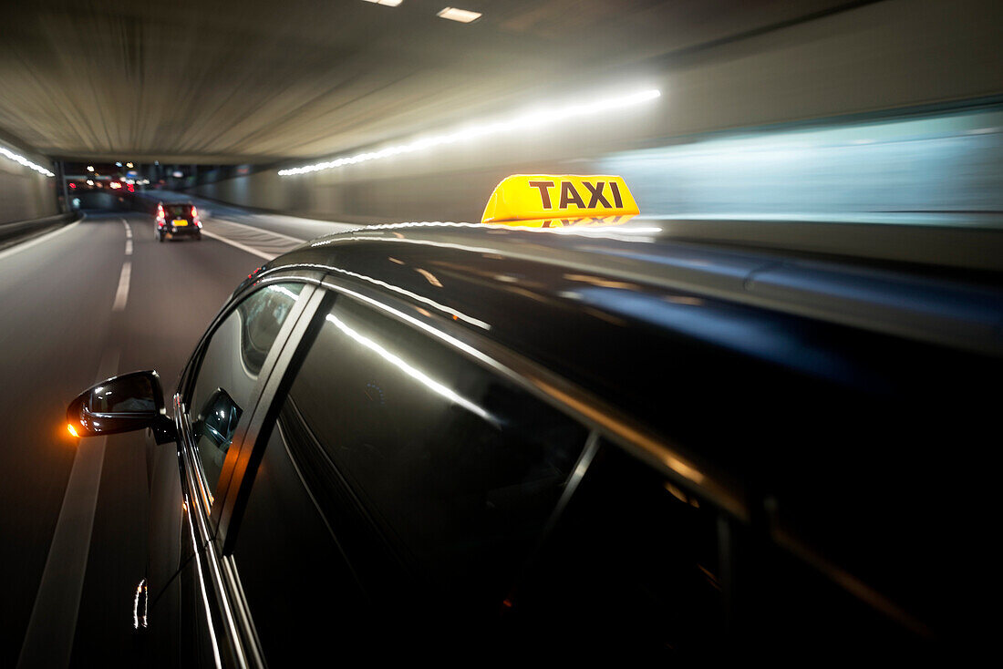 A taxi cab changing lanes in a tunnel. Driving behind other cars. Traffic.