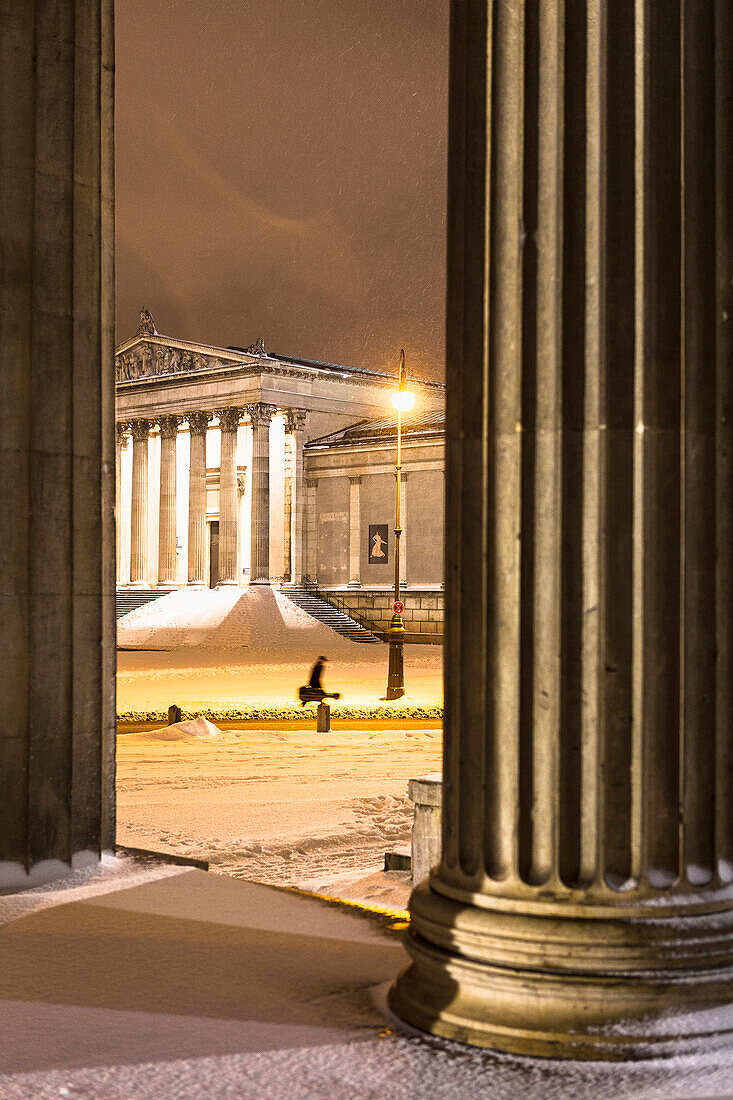 Königsplatz im Schneetreiben, Musiker läuft vor Antikensammlung zur U-bahn, Blick von Propyläen, München, Oberbayern, Bayern, Deutschland