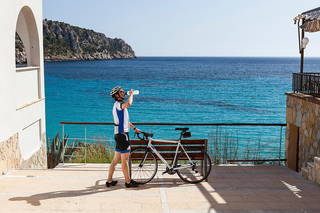 Bicycle rider drinking from a cycling bottle, Sant Elm, Majorca, Balearic Islands, Spain