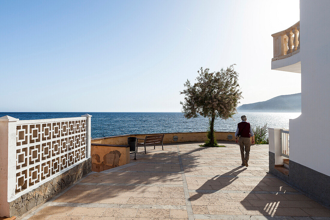 Old man strolling at Mediterranean coast in Sant Elm, Mallorca, Spain