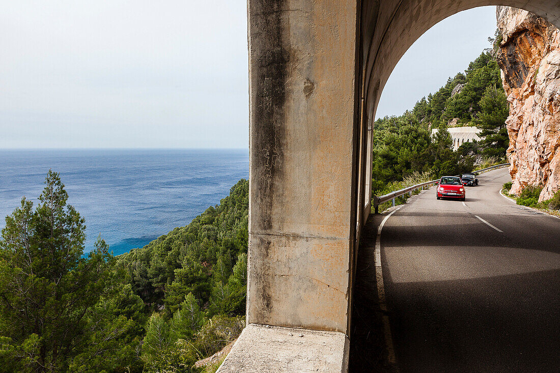 Two cars passing coast road tunnel at Mediterranean Sea, Estellencs, Mallorca, Spain