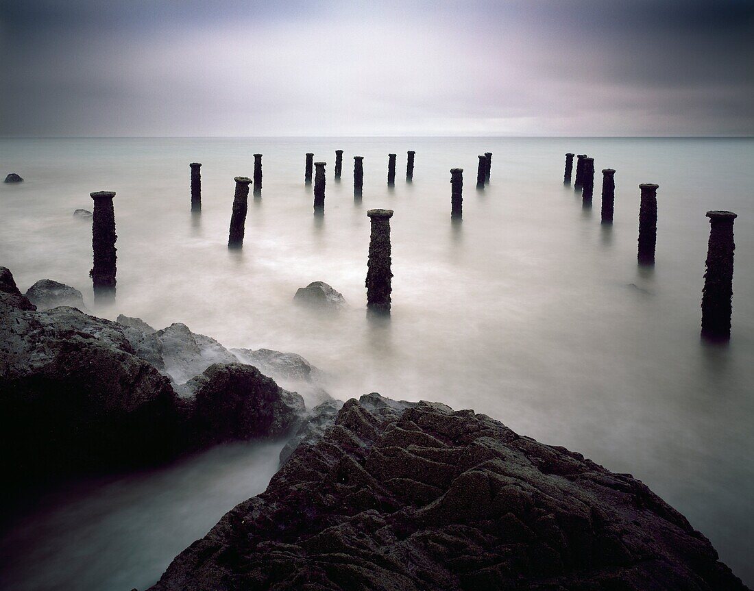 The pillars of the old pier under a grey stormy sky at Westward Ho! on the North Devon coast, England, United Kingdom