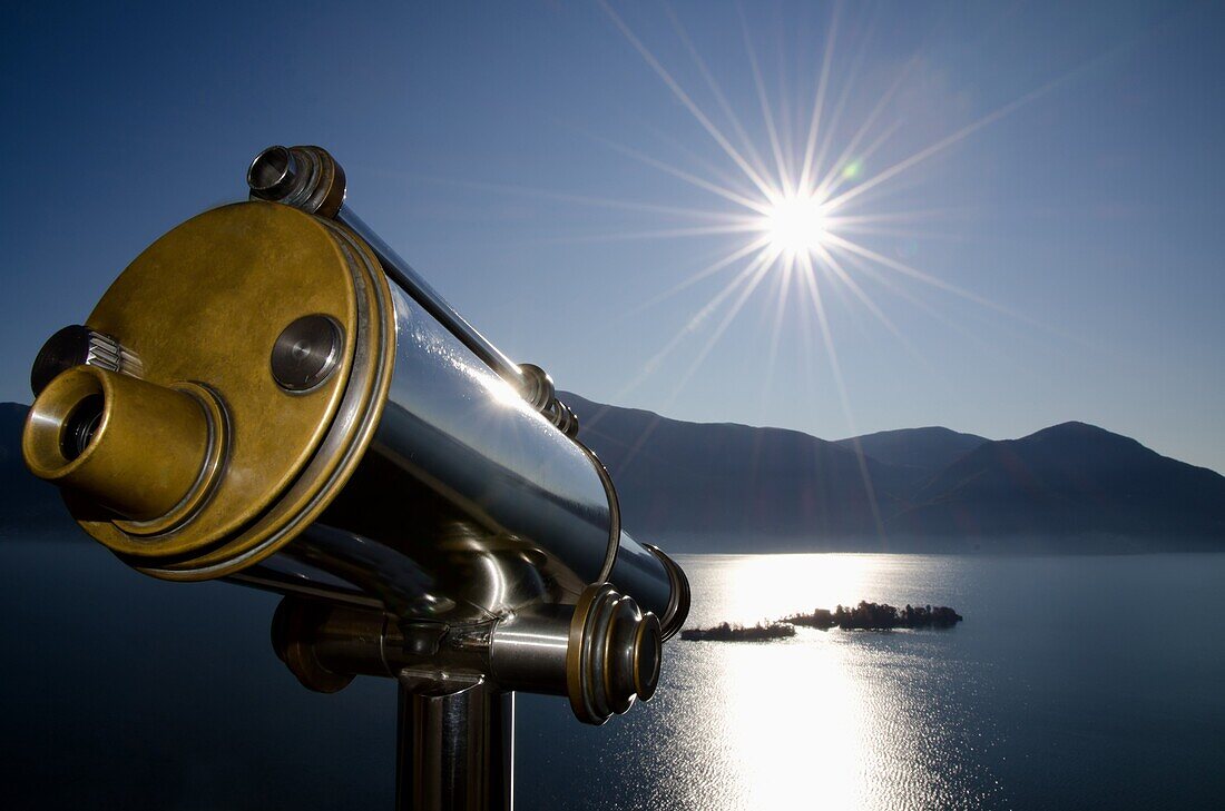 Watching with a telescope brissago islands on an alpine lake maggiore with mountains and sunbeam in switzerland