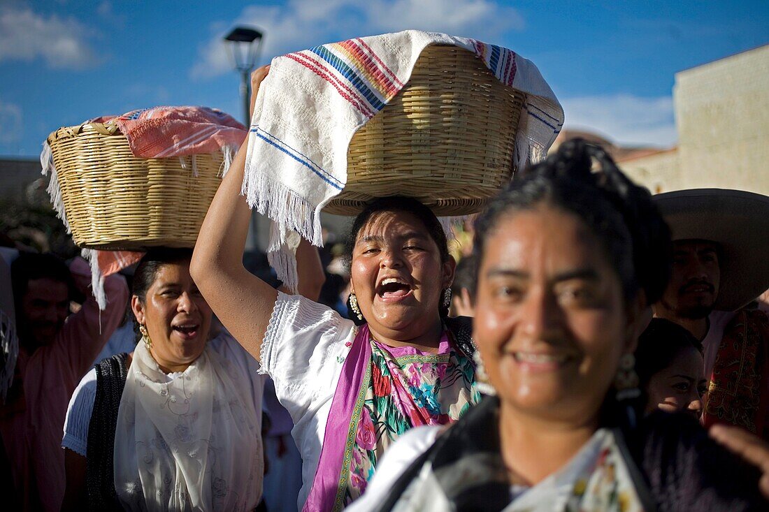 Women smile and carry baskets with food in their heads during the Guelaguetza parade in Oaxaca, Mexico, July 21, 2012  Oaxaca commemorates the ´Guelaguetza,´ an annual celebration by all seven of the state´s regions, as they converge on the capital to dem