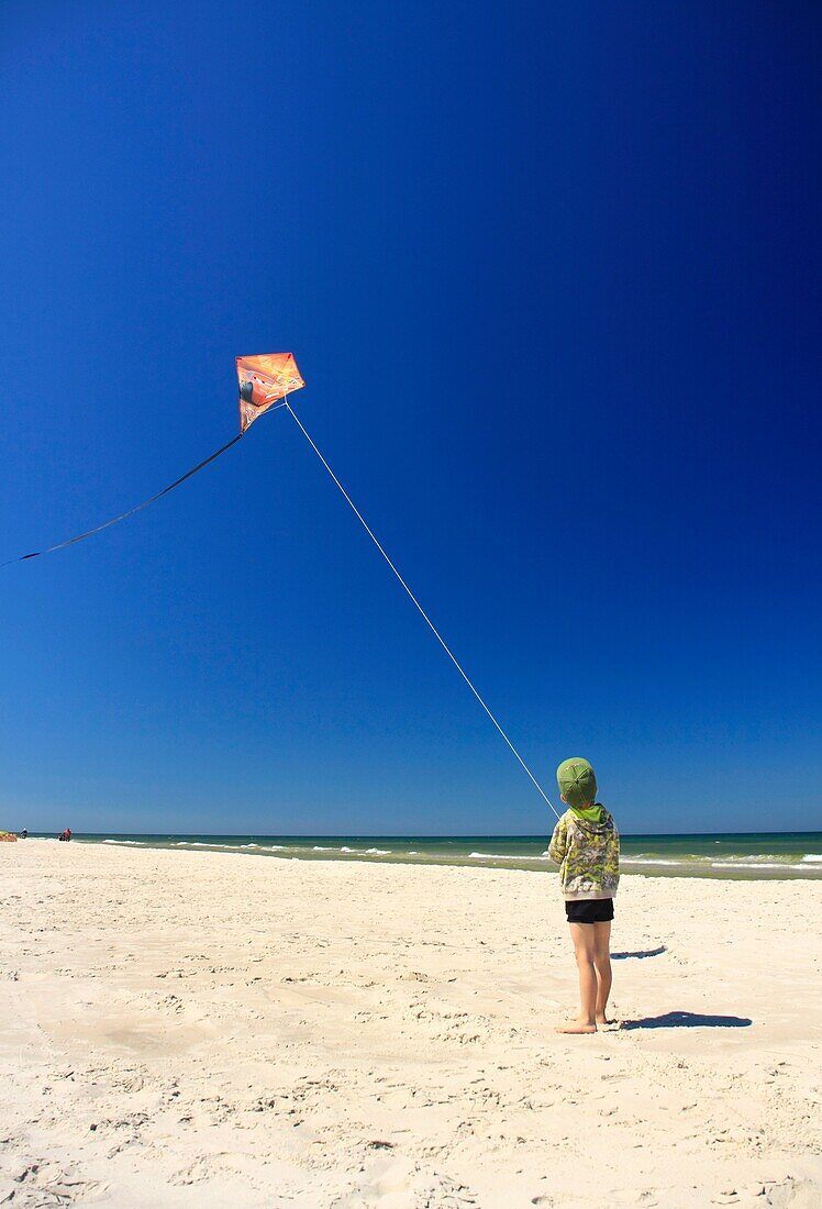 5 year old boy flying his kite on a beach