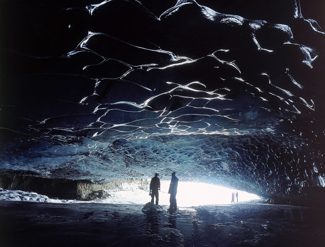 Men in Eyjabakkahellir Ice Cave, Iceland Tourists visit the Eyjabakkahellir ice cave on the Eyjabakkajokull glacier. Iceland