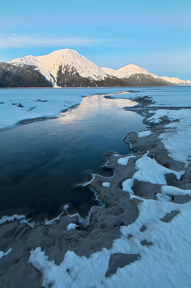 Morning light on the Kenai Mountains reflects on the waters and ice of Turnagain Arm, Southcentral Alaska, Winter. HDR