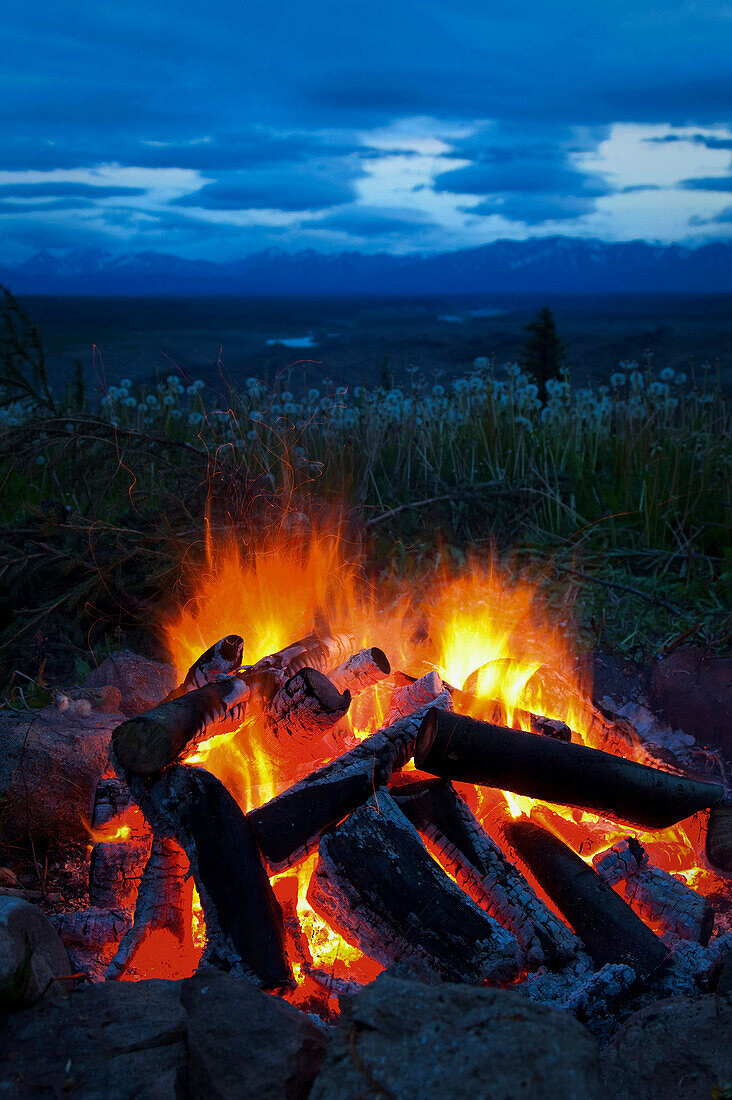 Close-up view of a camp fire with a view of the Chugach Mountain in the distance, Wrangell St. Elias National Park & Preserve, Southcentral Alaska