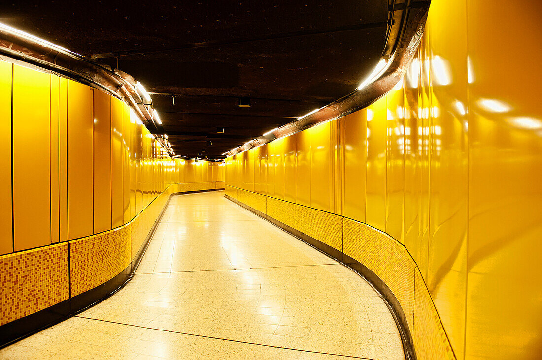 A tiled passageway in the underground Metro station. Vivid yellow colour.   Public transport space.