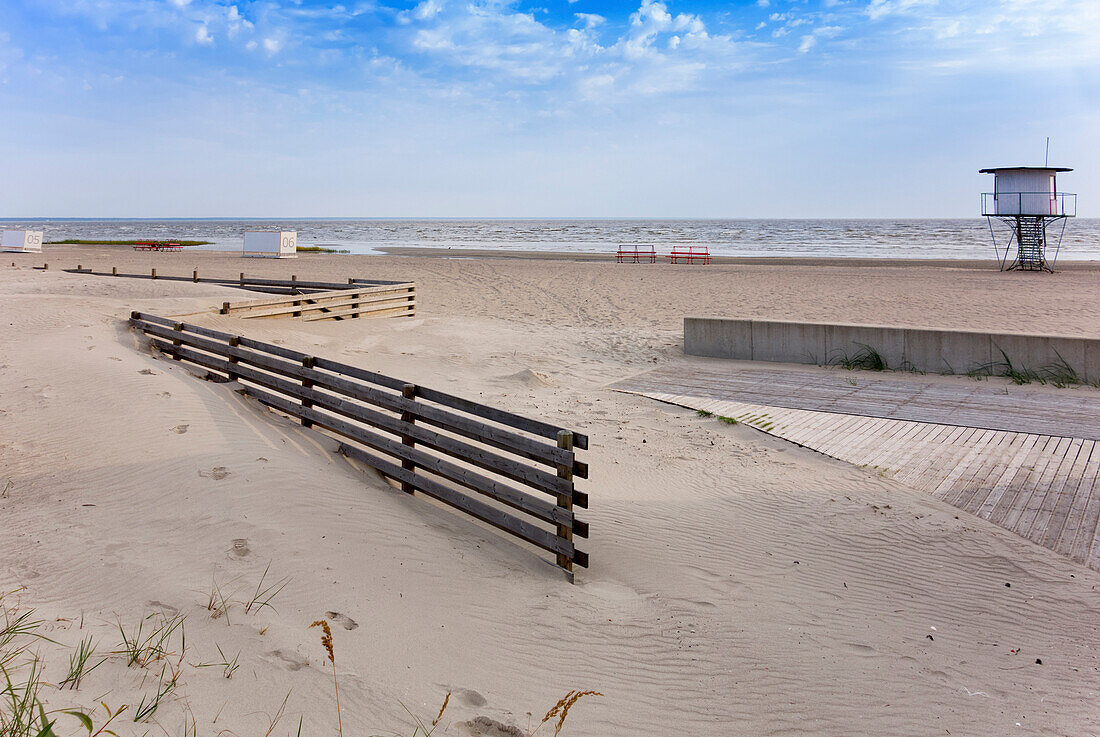 A beach resort on the Baltic sea coast. Sand and a viewing tower overlooking the sea. A slipway and a wooden fence.