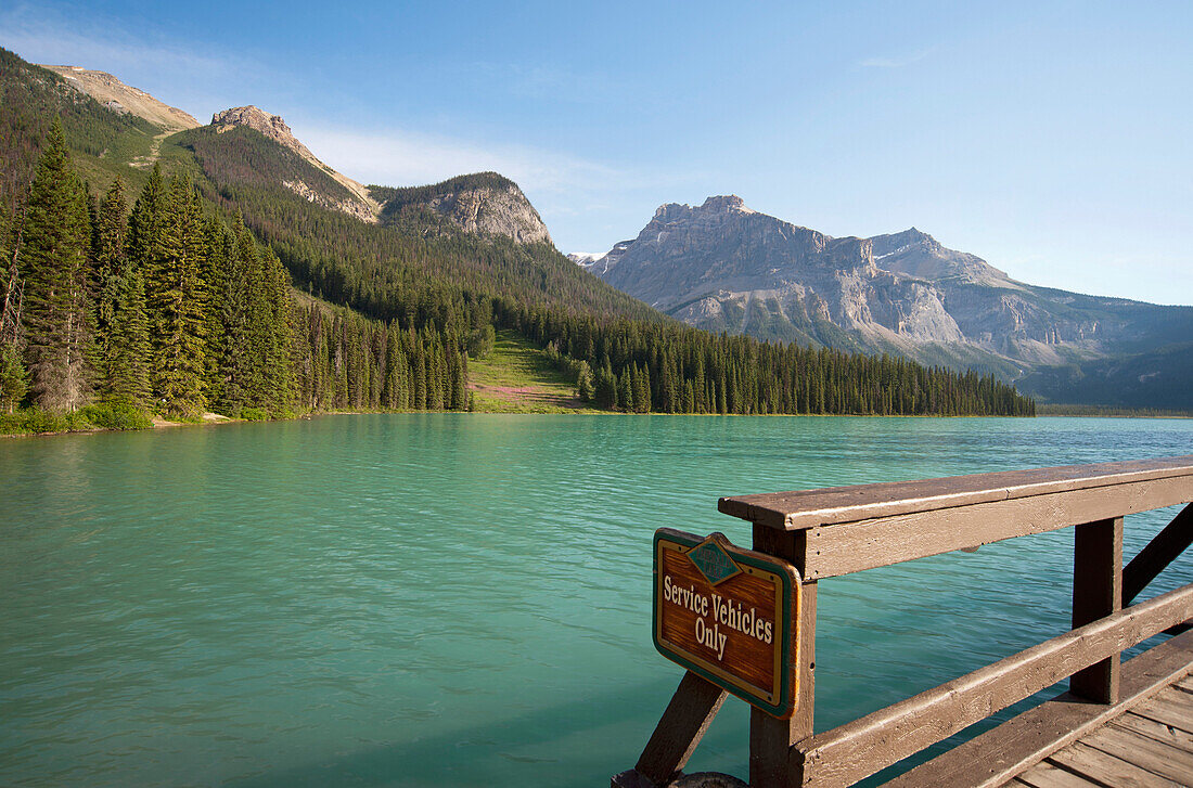 A view from a waterfront pier over the landscape of the Rocky Mountains surrounding the Emerald Lake and the brightly coloured waters of the lake