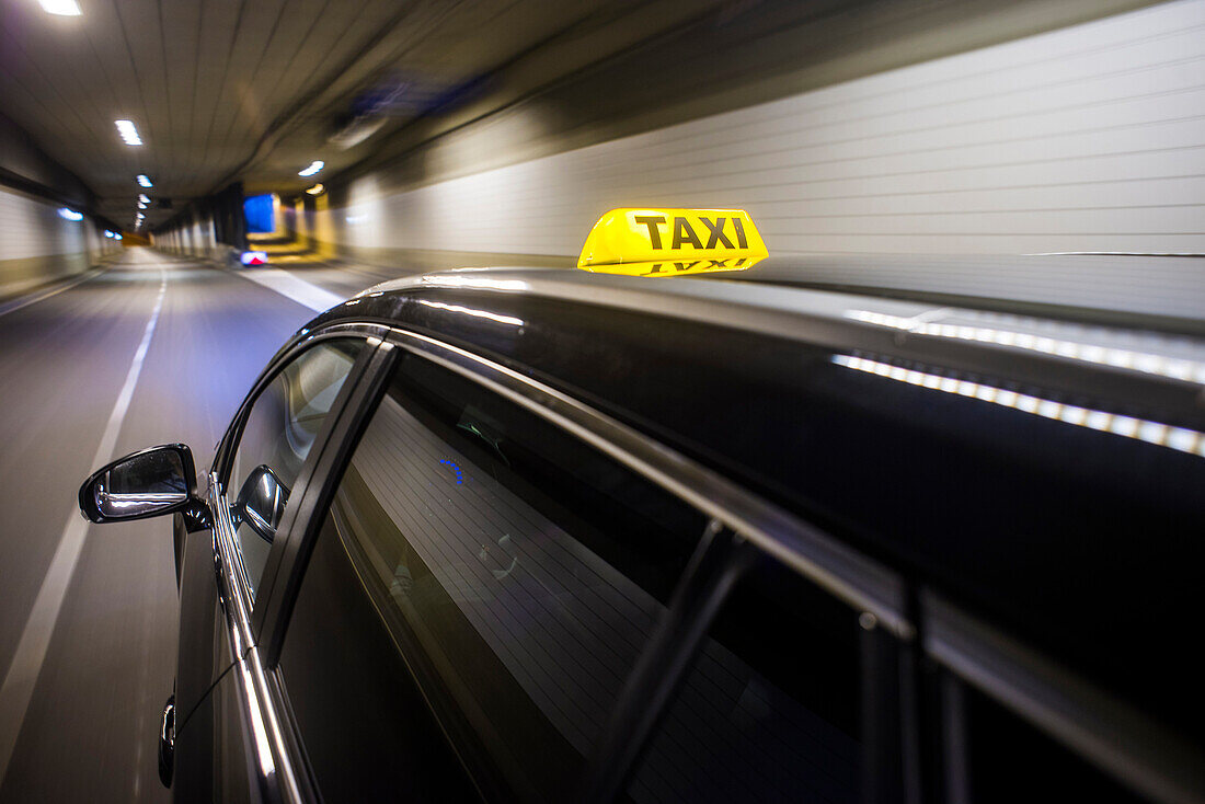 Taxicab with the roof light illuminated, driving at high speed through a tunnel