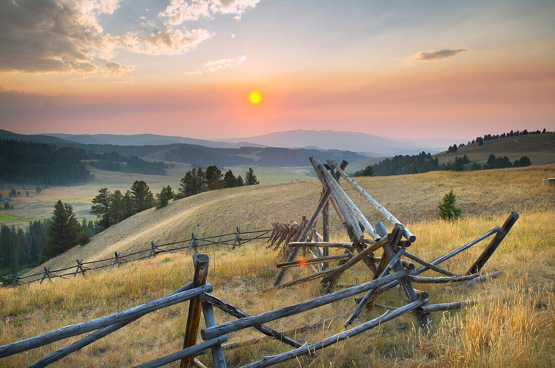 Sunset over the mountains and valleys of Montana, Strong wooden stock fencing on grasslands