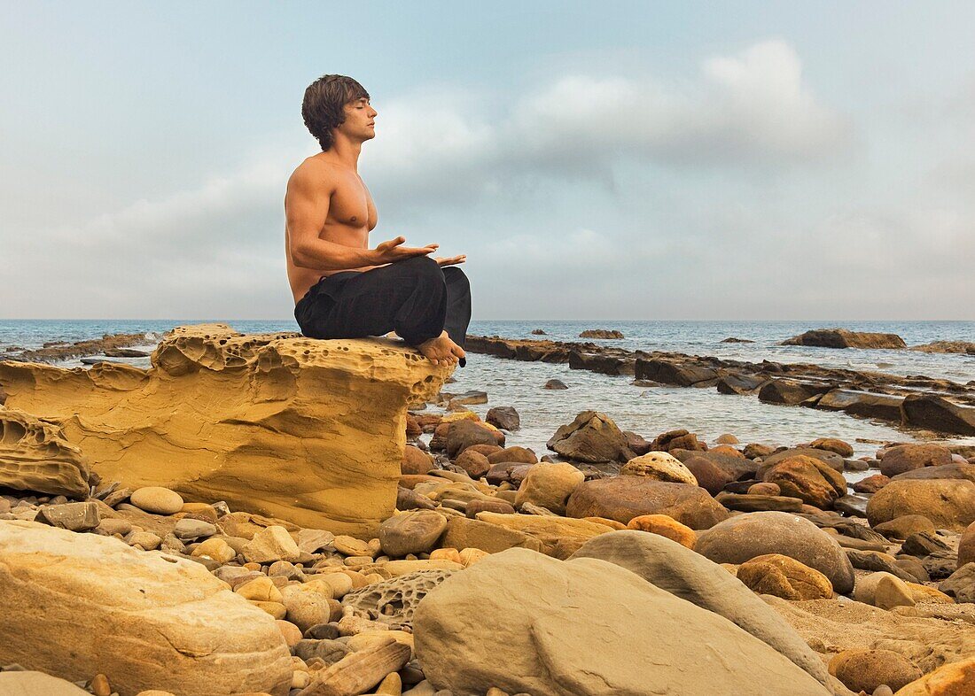 A Man Sitting In A Meditation Pose On A Rock Formation In Parque Natural Del Estrecho, Tarifa, Cadiz, Andalusia, Spain