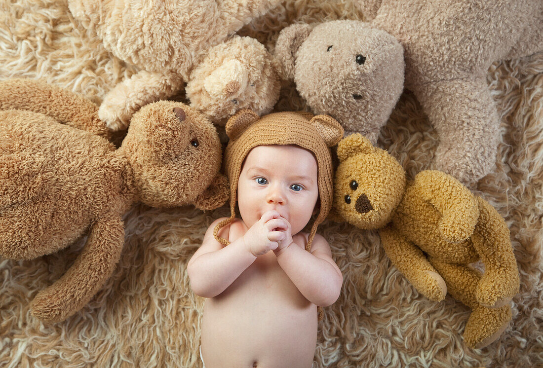 Baby Wearing Bear Cap Surrounded By Teddy Bears