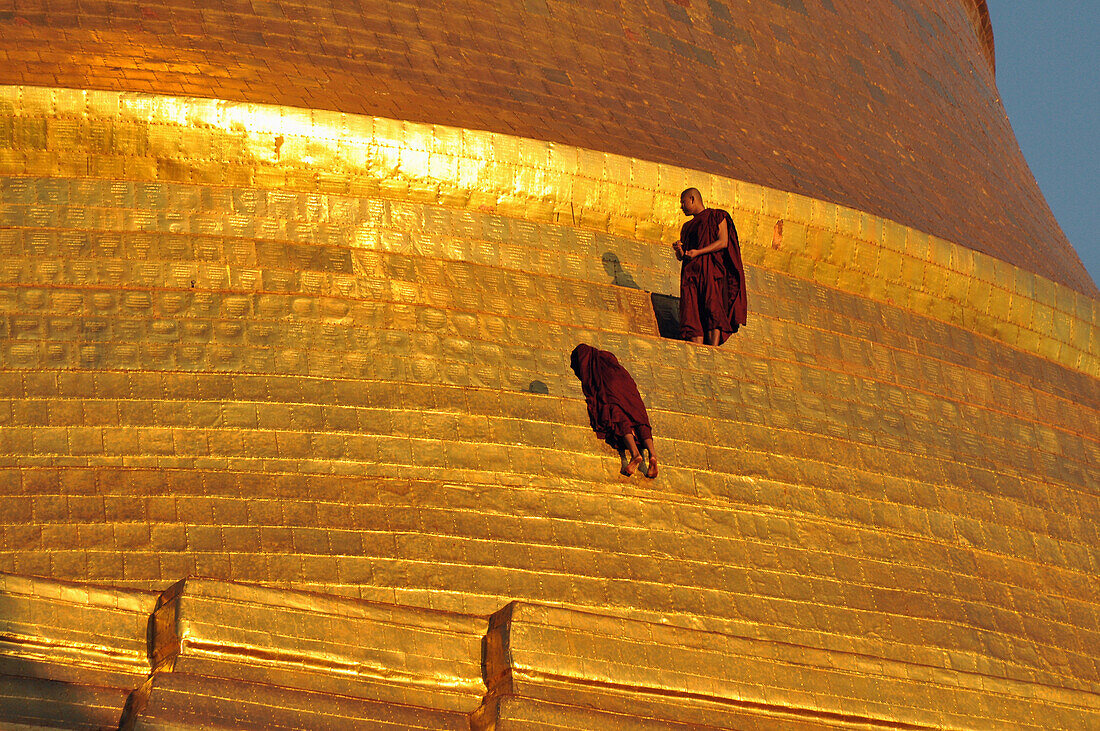 Two monks next to the golden wall of the Shwedagon Pagoda, Yangon, Myanmar, Burma, Asia
