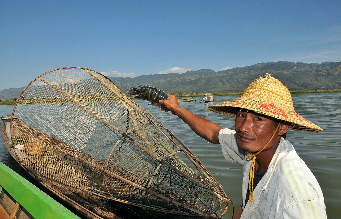 Fischer zeigt gefangenen Fisch auf dem Inle See, Myanmar, Burma, Asien