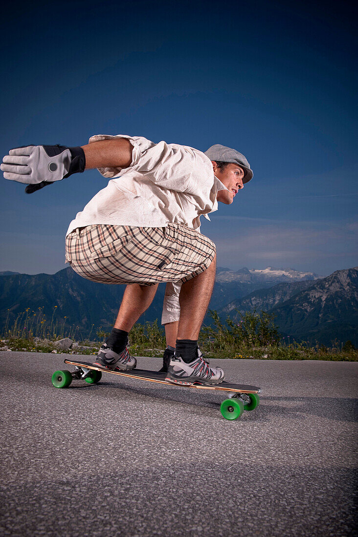 Mann fährt mit einem Longboard eine Straße entlang, Steiermark, Österreich