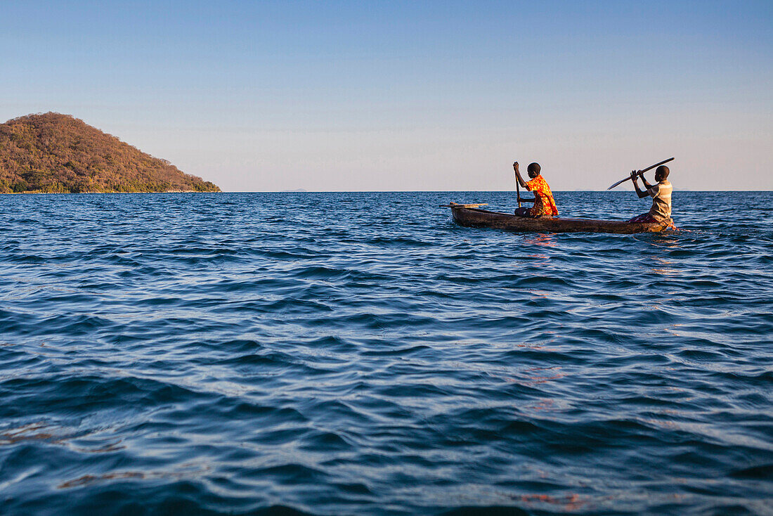 Two boys paddling in a dugout, a wooden canoe on Lake Malawi, Malawi, Africa