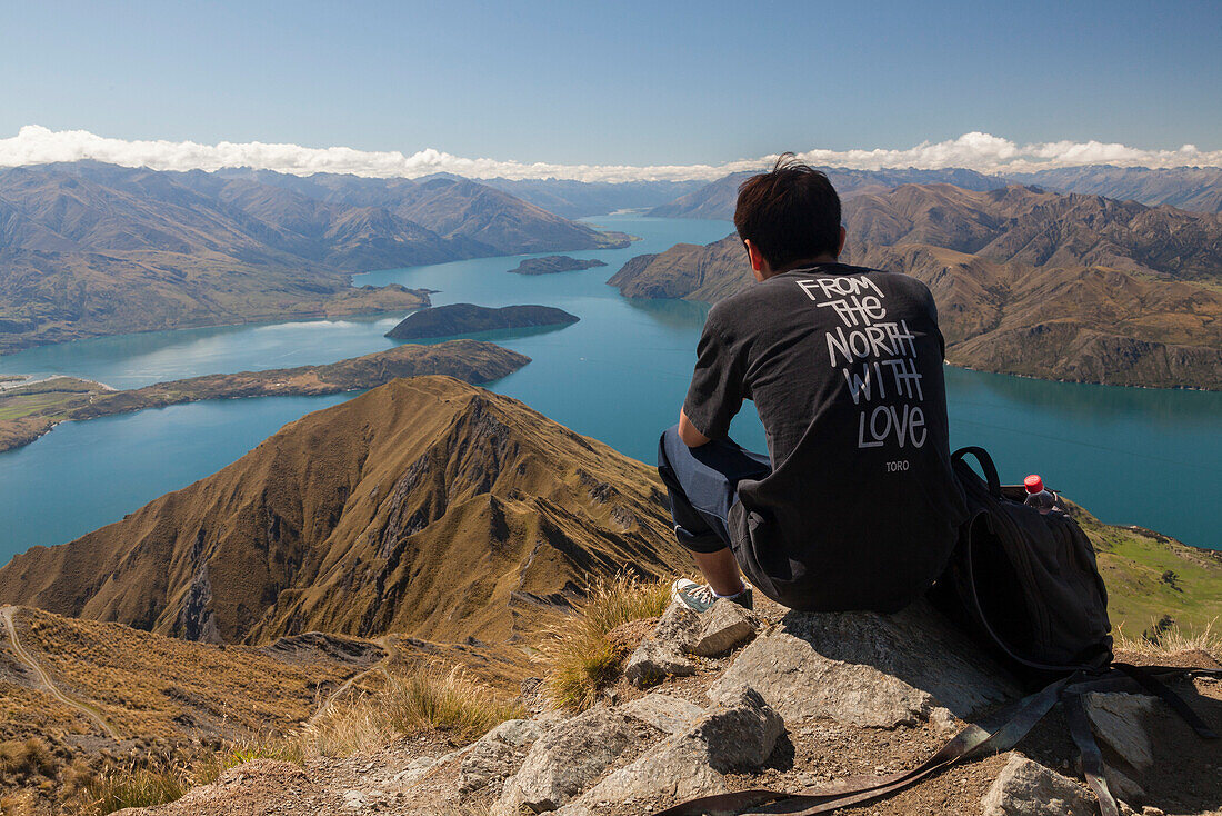 Aussicht vom Roys Peak über Lake Wanaka, junger Mann, Wanderer, oben auf Mount Roy, Südinsel, Neuseeland