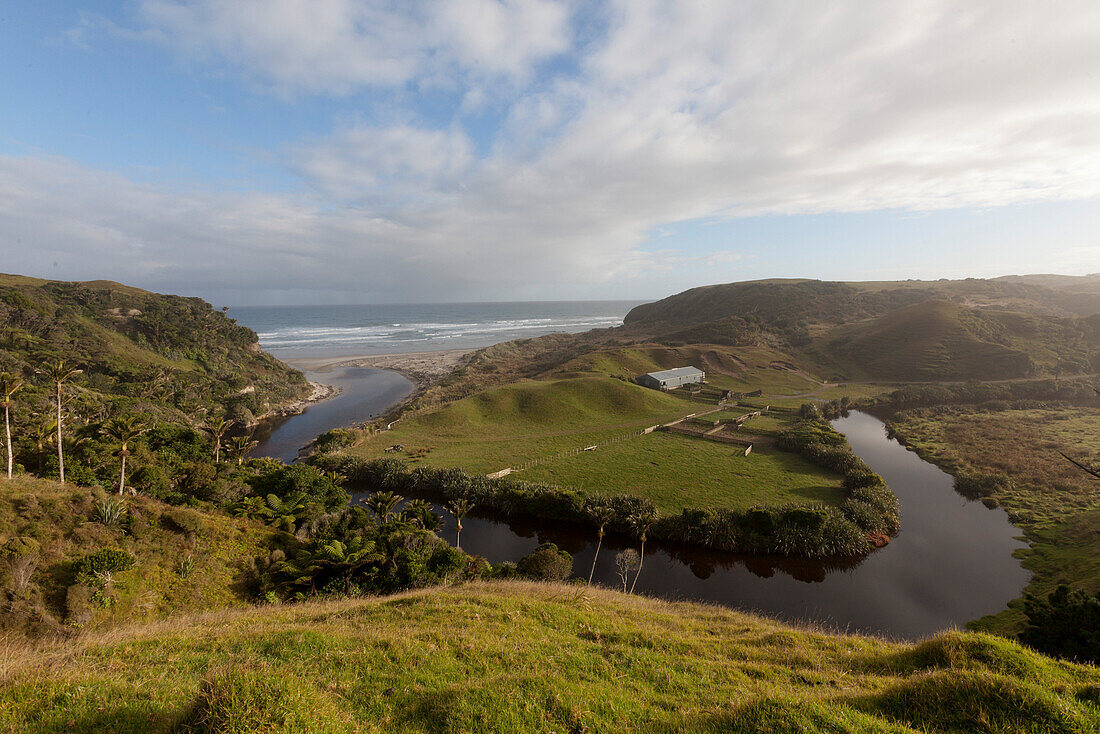 Farmland on the Anatori River estuary, pastures surrounded by arm of the river and coastline, west coast of South Island, New Zealand