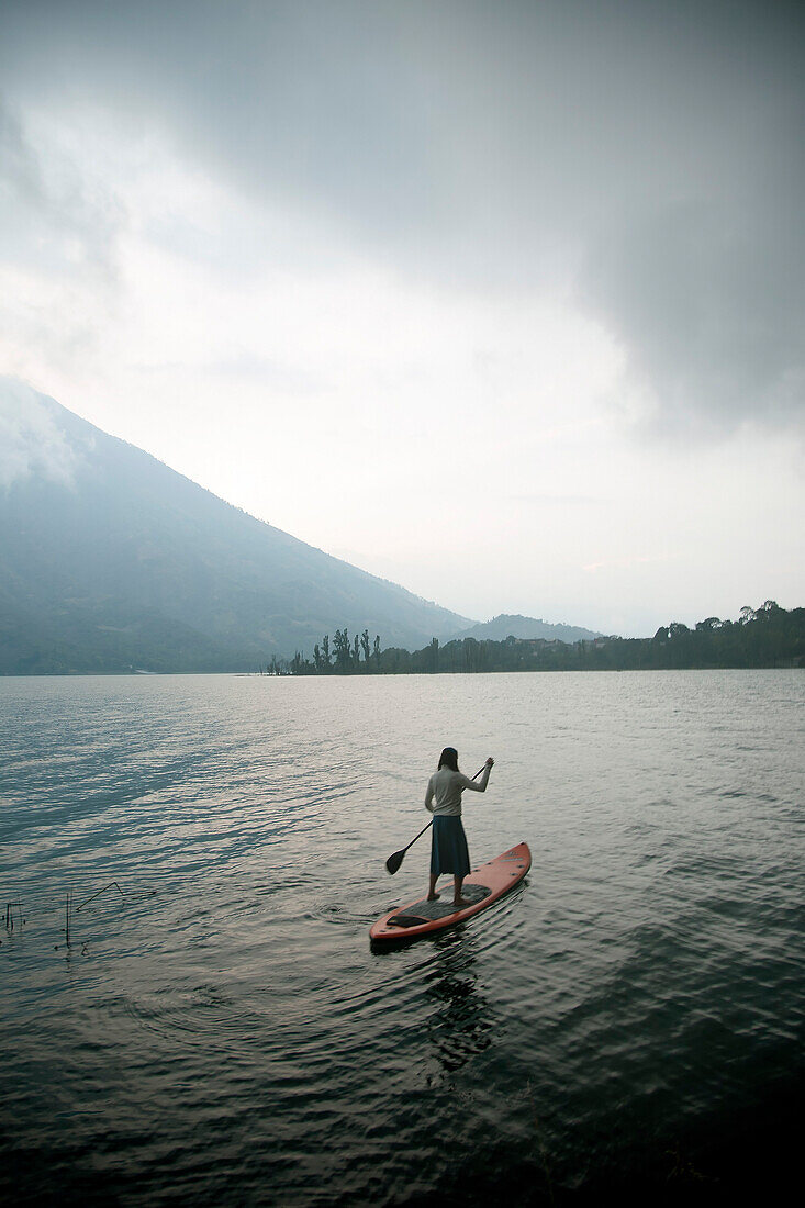 Woman Paddle Surfing on Misty Lake