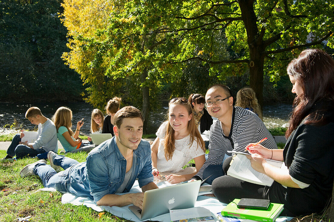Gruppe junger Leute lernt am Ufer der Dreisam, Freiburg im Breisgau, Schwarzwald, Baden-Württemberg, Deutschland