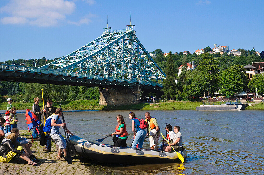 People and rubber boat on the bank of Elbe river, bridge Blaues Wunder in the background, Loschwitz, Dresden, Saxony, Germany, Europe