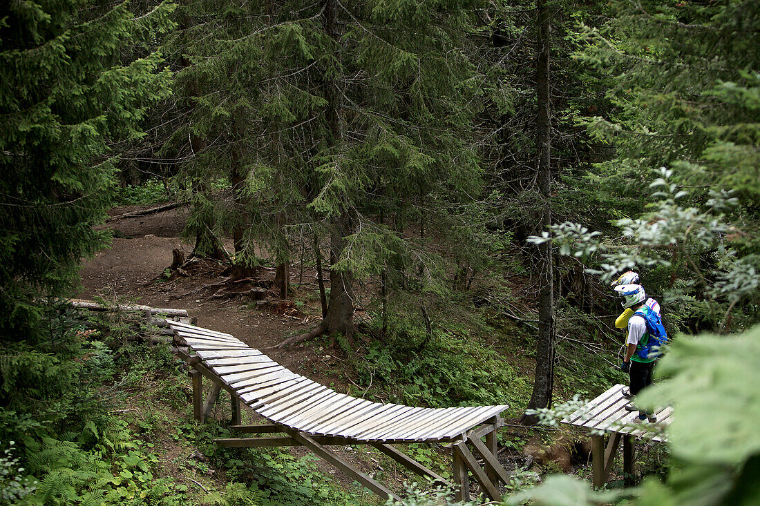 Zwei Freeride Mountainbiker im Gelände auf einem hölzernen Trail, Chatel, Haute-Savoie, Frankreich