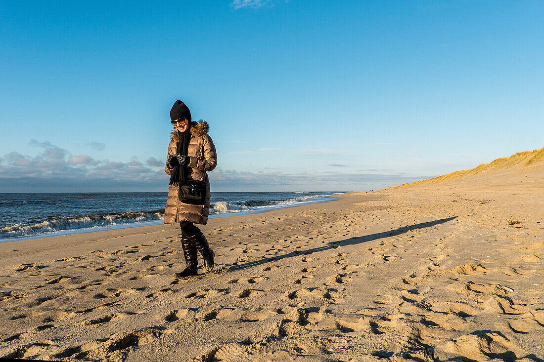 Woman walking along a beach in winter, Sylt, Schleswig-Holstein, Germany