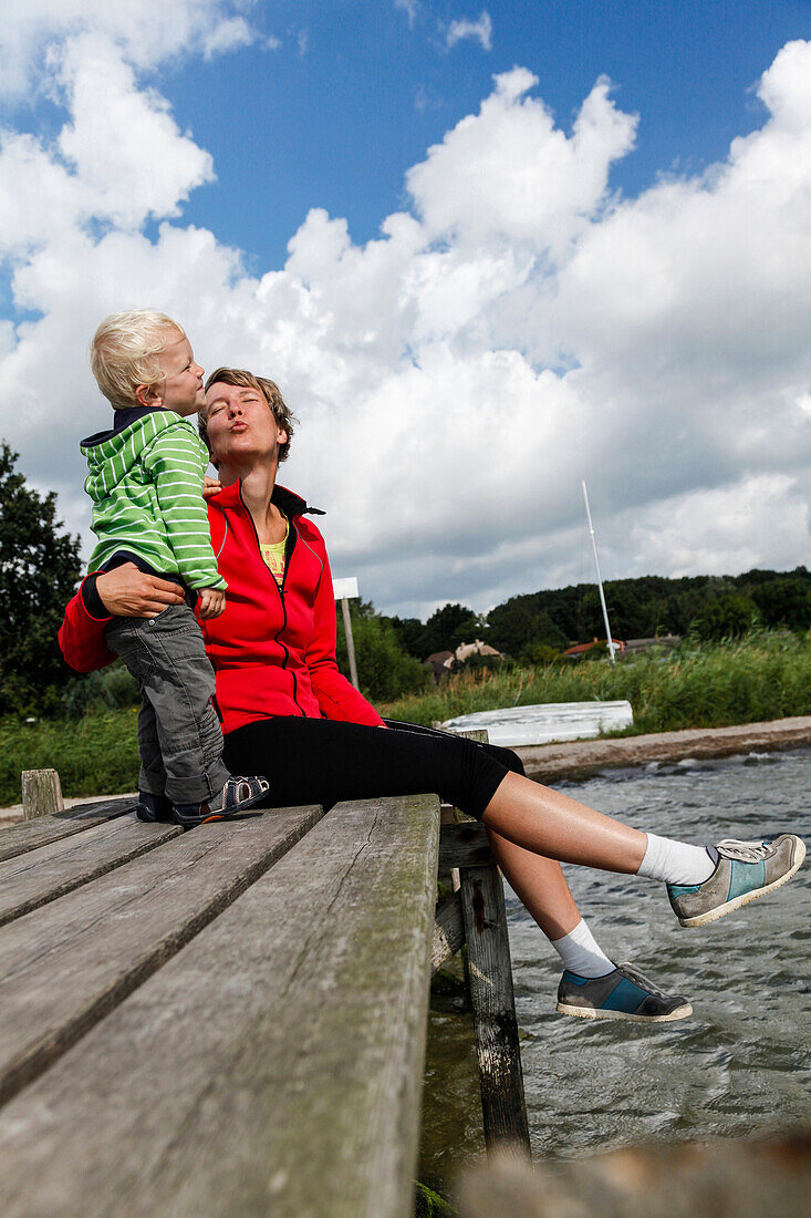 Mother and son (2 years) sitting on a jetty at Baltic Seashore, Muglitz, Island of Ruegen, Mecklenburg-Western Pomerania, Germany